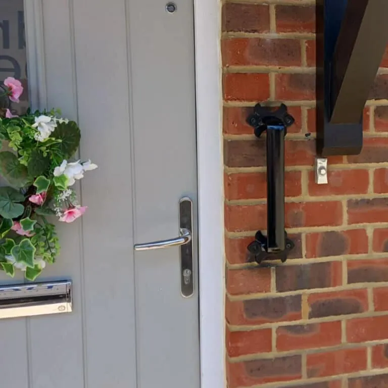 Short metal grab rail fitted by a front door step The Handrail People